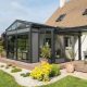 Véranda aluminium Installux gamme Luciole attenante à une maison contemporaine avec terrasse en bois et jardin paysager